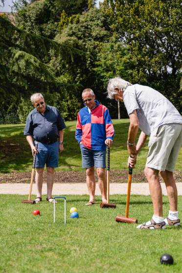 Seniors playing croquet on a sunny day