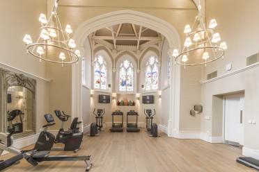 Gym equipment in high, bright room with stained glass windows