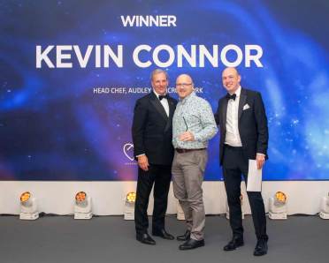 Three men in formal attire stand smiling in front of a backdrop with the text "Winner Kevin Connor, Head Chef, Audley Cooper's Hill York.