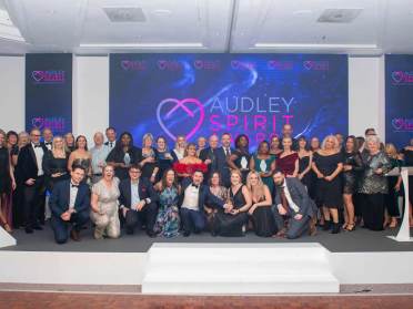 Audley Spirit Award Winners 2024 A large group of people in formal attire pose on stage in front of a display that reads "Audley Spirit Awards.